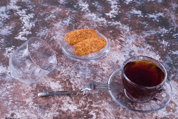A cup of espresso with sesame cookies in a glass saucer on the marble