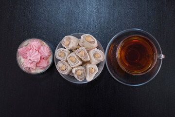 Marshmallows and turkish lokum in glass cups with a cup of tea, top view