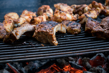 Marinated meat on the barbecue with red charcoal, chicken and ribs
