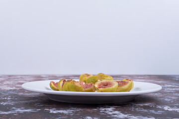 Yellow figs with red seeds in a white plate in minimalistic style