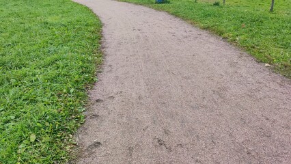 Sandy path in the park. A sandy footpath runs through the green mowed lawn. Autumn, green grass,...