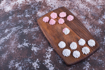 White and pink flower shaped marshmallows on a wooden platter, angle view