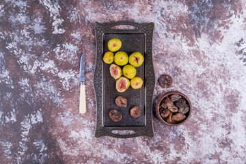 Whole, dry and sliced figs in a metallic tray and in a wooden cup in the middle