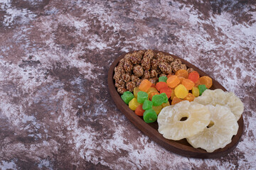 Marmelades and dry sliced fruits in a wooden platter, top view