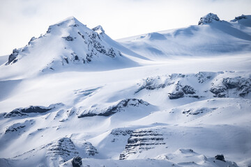 Mountain ridge covered with snow under overcast sky