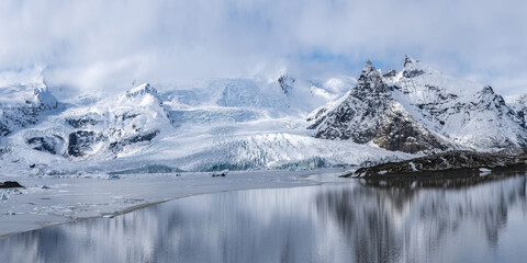 Snowy rocky mountains at lakeside on winter day
