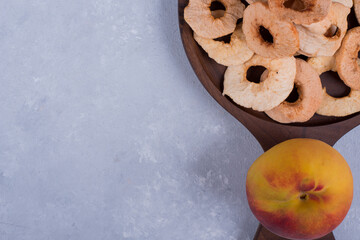 Peeled, sliced and dry apples with a peach on a wooden platter