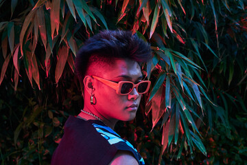 Stylish non binary person under neon light