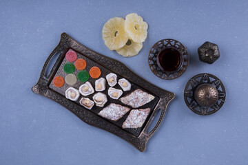 Metallic pastry platter with delights and a glass of tea