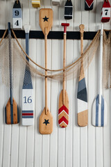 Several colorful wooden paddles hang on a white wall or fence. canoe paddles for active water...