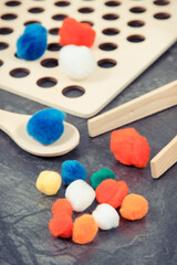 Obraz na płótnie Canvas Colorful pompoms using for playing and development of kids motor skills, coordination and logical thinking