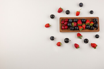 Naklejka na ściany i meble Berry mix on a wooden platter and on the white background in the corner