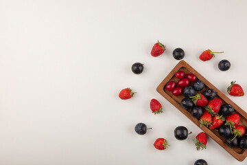 Berry mix on a wooden platter and on the white background