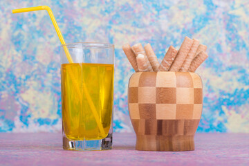A glass of juice with waffles sticks in a wooden cup