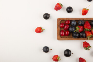 Naklejka na ściany i meble Berry mix on a wooden platter and on the white background