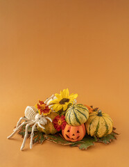 Autumn and halloween 2022. Fall flower , pumpkin and squash arrangement with spider skeleton. Many varieties of flowers an squashes on orange  background. Minimal composition.