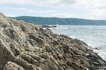 coastal cliff formed by solidified lava close-up against the background of a distant sea shore