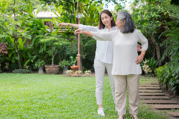 An old elderly Asian woman and exercise in the backyard with her daughter.  Concept of happy...