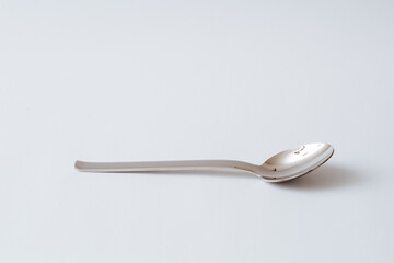 Stainless steel teaspoon on white background, kitchenware, copy space, close-up