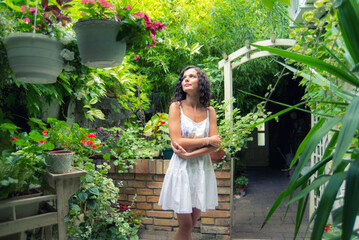 Young smiling woman standing in her home garden on a beautiful spring day
