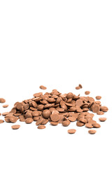 Close up of milk chocolate chips. Scattered chocolate callets isolated on white. Texture of chocolate. Vertical photo