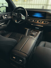 Interior of a luxury vehicle. New, modern design, steering wheel with buttons and switches, screen.