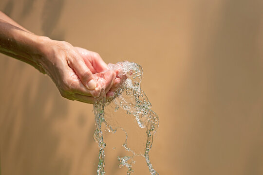 Close up of a female wet hands with water gliding over it on a b