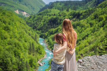 Naklejka na ściany i meble Mom and son tourists on the background River bend, Montenegro,.natural landscape, mountain river Tara Portrait of a disgruntled girl sitting at a cafe table