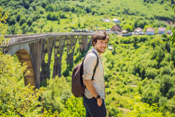 Montenegro. Man tourist in background of Dzhurdzhevich Bridge Over The River Tara. Travel around...