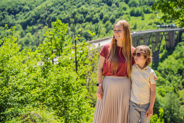 Montenegro. Mom and son tourists in background of Dzhurdzhevich Bridge Over The River Tara. Travel...