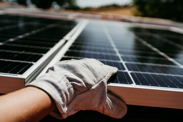 close up of hand of mature Technician man touching solar panels on house roof for self consumption...