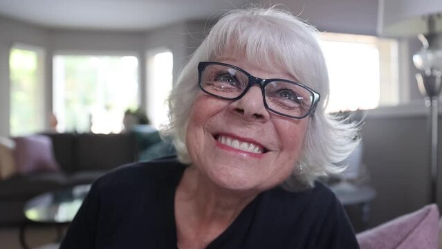 Slow motion close up of mature, senior citizen woman laughing and smiling at home. 
