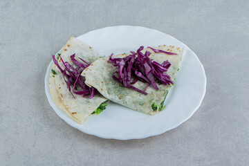 A plate of gutab with red shredded cabbage , on the marble background