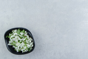 Sliced greens and cabbage in bowl , on the marble background