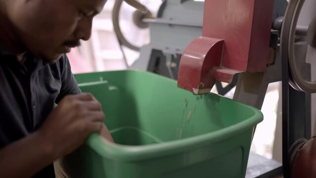 An Hispanic farmer is colecting coffee beans from the peeling machine