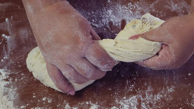 The hands of a Jewish woman knead the dough for baking festive challah. Medium plan