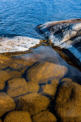 Stones in the water, rocks in the sun and blue water in the Bothnian Sea, Sweden.