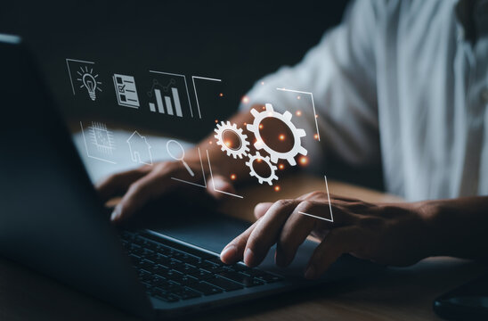 Businessman Typing On Laptop Keyboard Showing Cogwheel Virtual Screen. Concept Of Using Automation Technology To Increase Efficiency And Effectiveness The Marketing Work Of Corporate Business