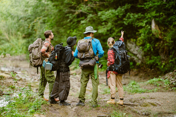 White young travelers with backpacks hiking together in forest