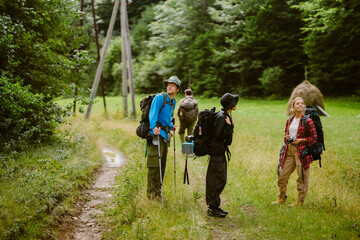 White young travelers with backpacks hiking together in forest