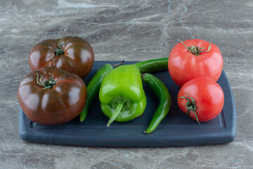 Tomatoes and peppers on the tray , on the marble background