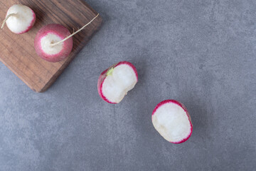 Delectable radishes with board , on the marble background
