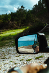 sea reflection in car rear mirror. road trip