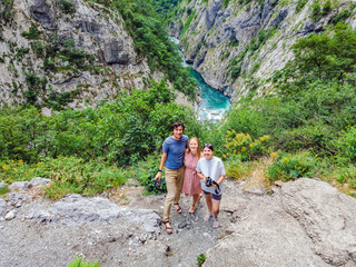 Friends tourists on background of purest waters of the turquoise color of the river Moraca flowing...