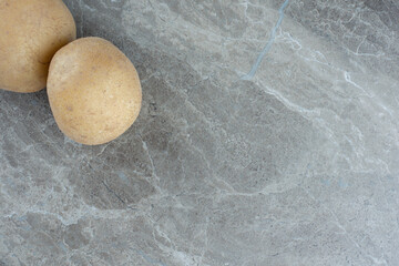 Two ripe potatoes , on the marble background