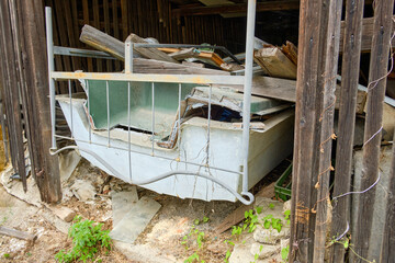 Neglected plastic boat full of junk in a derelict barn.