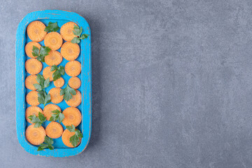 Greens and sliced carrot on the wooden tray , on the marble background