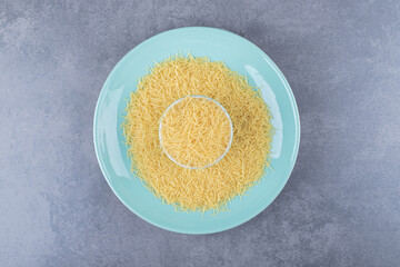 Heap of raw macaroni on blue plate
