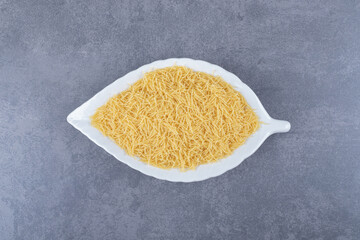 Heap of raw macaroni on leaf-shaped plate