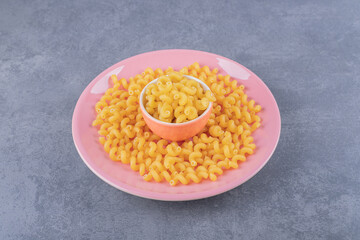 Raw dry macaroni on pink plate